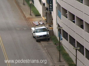 Parked truck and streetlight poles both block sidewalk.
